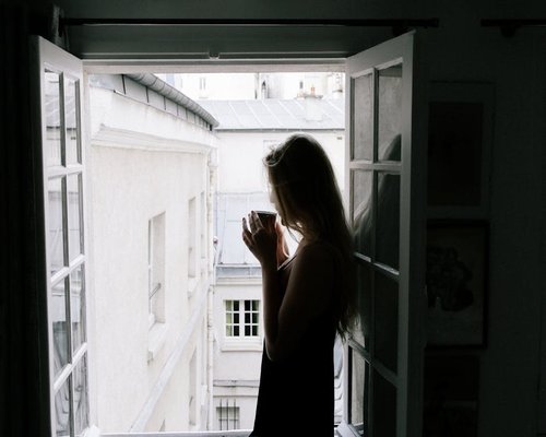 Woman drinking coffee next to an open window in a modern Mexico City apartment