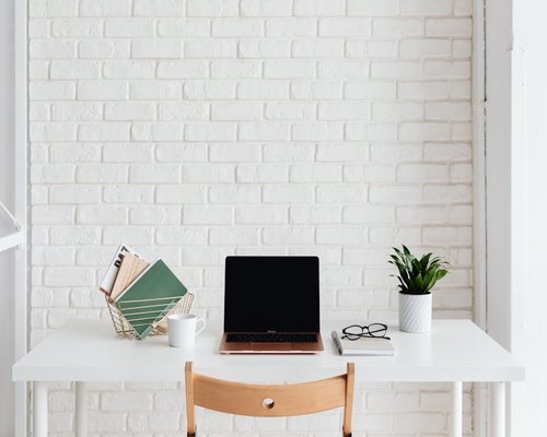 A well lit minimal desk with plants and books